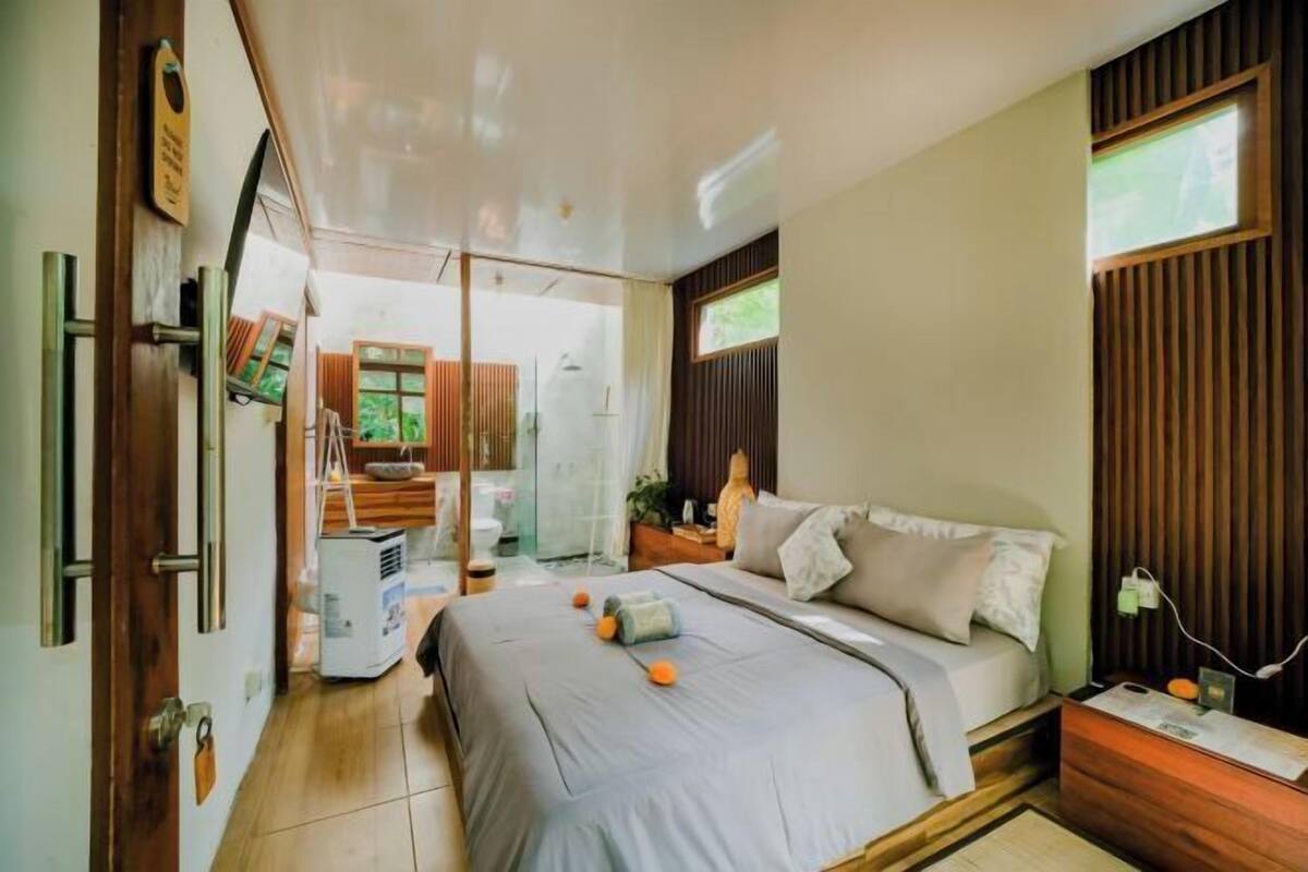 Un dormitorio con cama, mesita de noche y ventana.