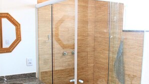 A bathroom with a wooden vanity, a glass shower enclosure, and a marble countertop. - Hotel Santo Afonso (Aparecida)