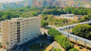 A hotel with multiple floors, a central courtyard, and a view of a cityscape with a prominent building in the background. - Hotel Santo Afonso (Aparecida)