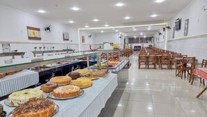 A buffet area with various food items and a long counter. - Hotel Santo Afonso (Aparecida)