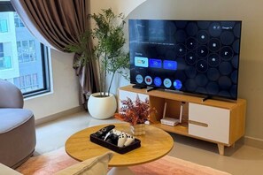A modern living room with a flat-screen TV, a potted plant, and a coffee table. - Suria Garden by Iconique (Puchong)