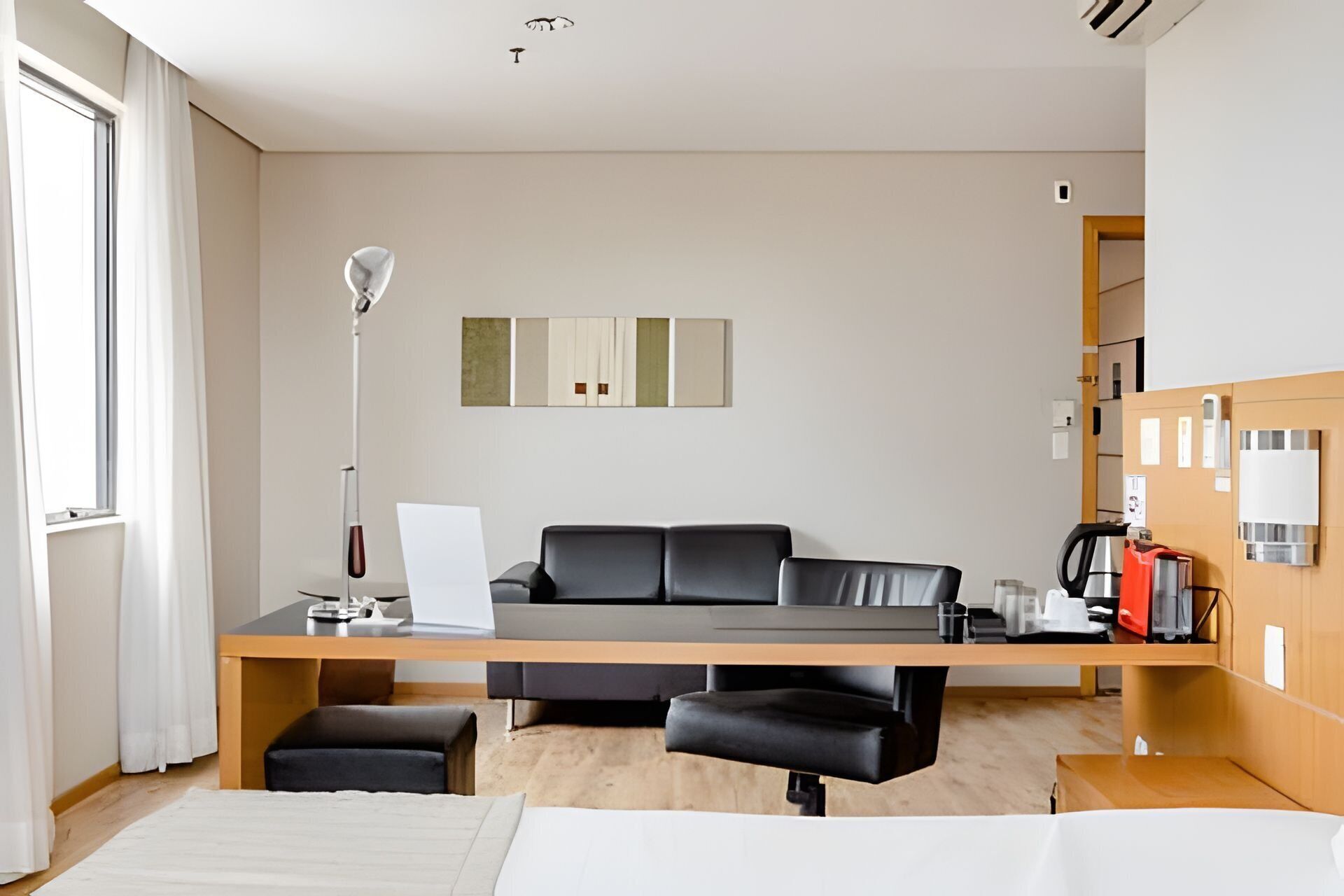 Una habitación de hotel moderna con sofá, escritorio, cafetera y cama.