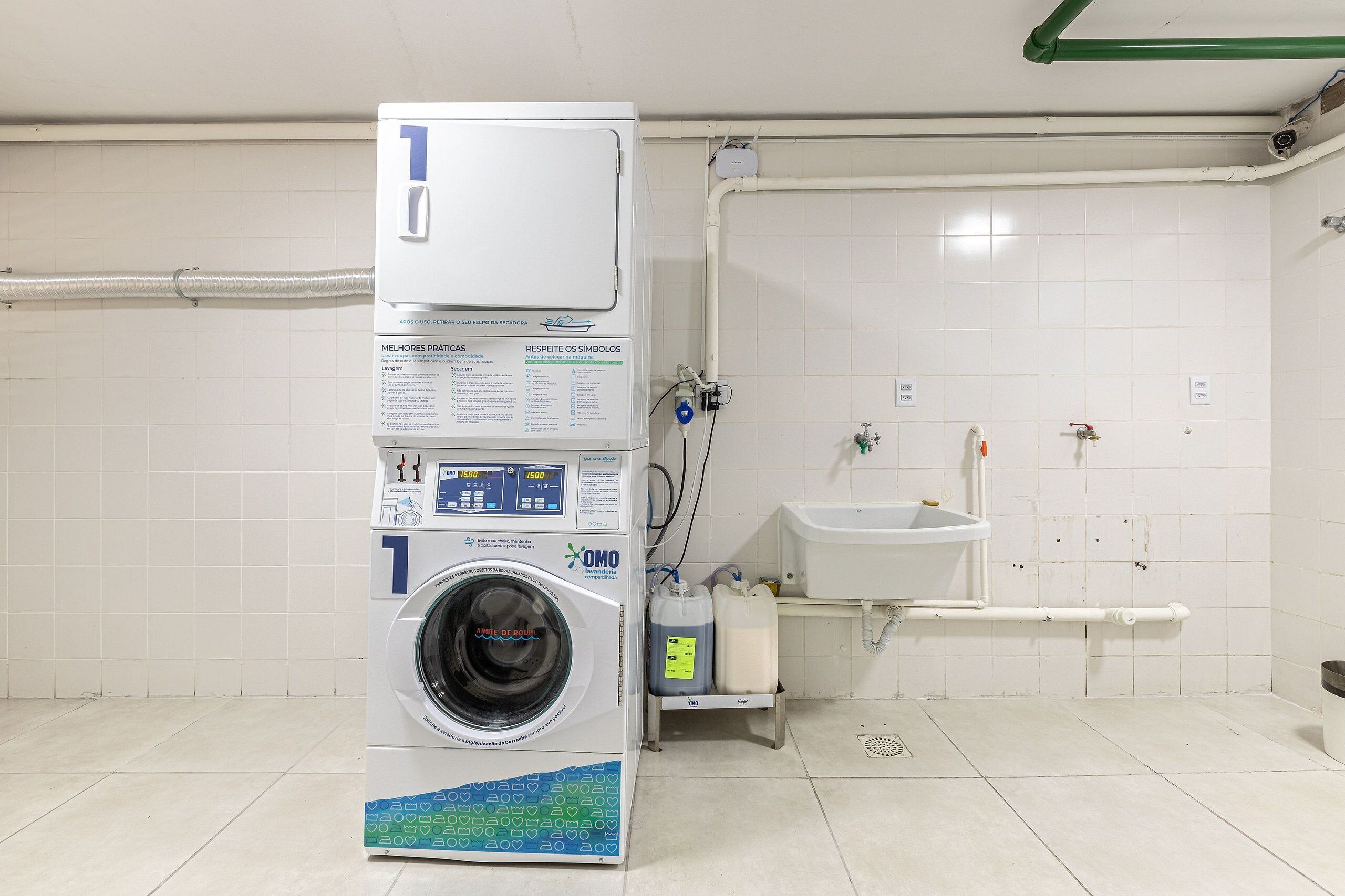 A public laundry facility with a washing machine, a sink, and a toilet.