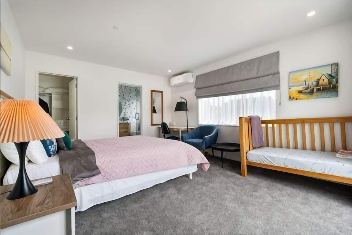 A bedroom with a bed, bedside table, lamp, chair, and a small table with a lamp.