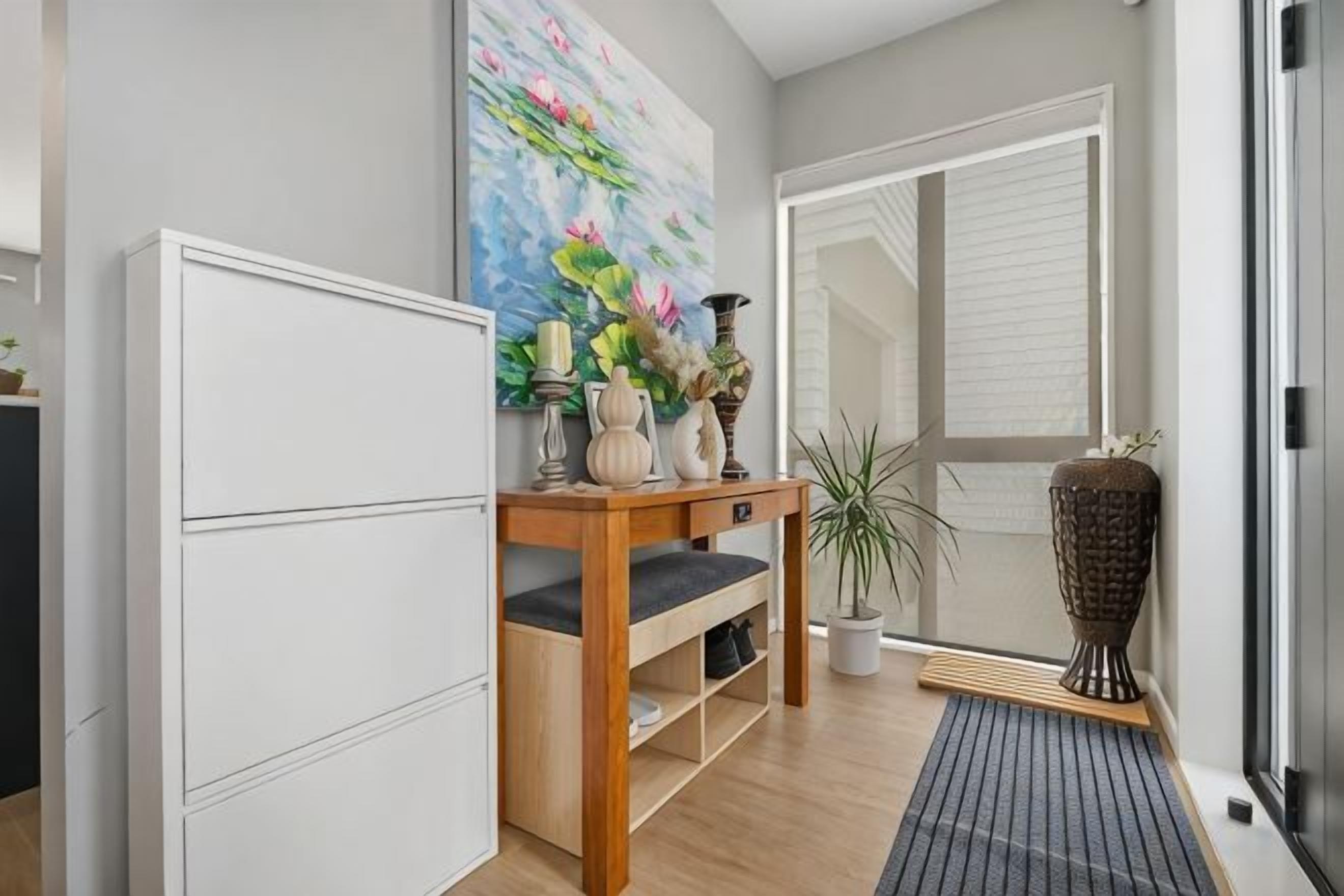 Quarto com mesa de console de madeira, planta em vaso e um vaso grande.
