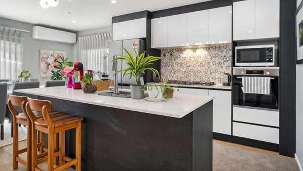 A modern kitchen with a central island, white cabinetry, a microwave, and a coffee machine. - Auckland Cornwall Park Holiday Homes1 (Auckland)