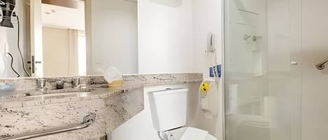 Un baño con encimera de mármol, inodoro, cabina de ducha de cristal y espejo.
