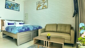 A bedroom with a bed, a sofa, a coffee table, and a wall with artwork. - Silk Valley-Prime located cozy studio (Abu Dhabi)