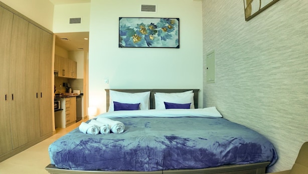 A bedroom with a bed, pillows, and a painting on the wall. - Silk Valley-Prime located cozy studio (Abu Dhabi)