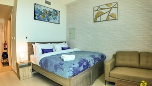 A bedroom with a bed, a nightstand, a sofa, and artwork on the walls. - Silk Valley-Prime located cozy studio (Abu Dhabi)