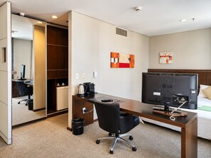 A hotel room with a desk, chair, bed, and a television. - 1-bedroom apartment, with a pool, near Alphaville | 1105 (Osasco)