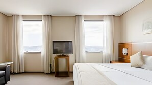 A hotel room with a bed, a TV, a desk, and a view of the outdoors. - Apartment with 1 parking space | UN1105 (Osasco)