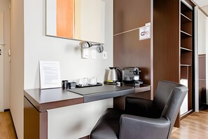 Una habitación de hotel moderna con kitchenette, un escritorio y una silla.
