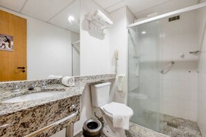 Un baño con lavabo de granito, inodoro, cabina de ducha de vidrio y perchero para toallas.