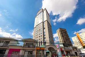 A multi-story building with a modern architectural design, featuring a prominent entrance with a glass canopy and a sign for a business establishment. - Hospedez - Spacious apartment w/cupboard ap1701 (Osasco)