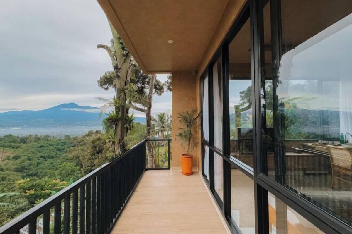 Un balcón con vistas a un paisaje montañoso, una planta en maceta y un área de comedor con mesa y sillas.