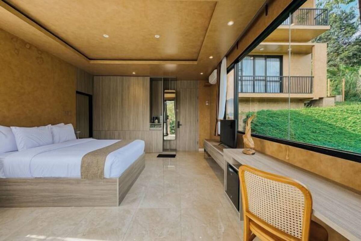 Un dormitorio moderno con una cama grande, un escritorio y vistas a un balcón.