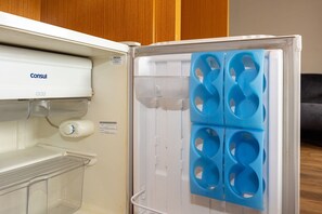 Un refrigerador con dispensador de agua, un cajón de almacenamiento de plástico transparente y un compartimento para hielo azul.