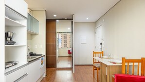 Een kleine keuken met witte kastjes, een koffiezetapparaat en uitzicht op een balkon.