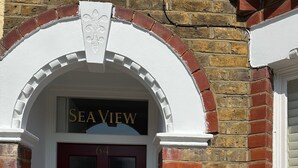 A red door with a brass knocker and a sign above it that reads "SEA VIEW".