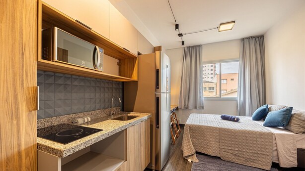 A compact kitchenette with a built-in microwave, a stainless steel refrigerator, and a granite countertop.