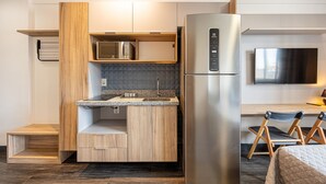 A compact kitchen with a built-in microwave, a stainless steel refrigerator, and a wooden countertop.