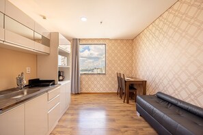 A modern kitchen with a large window, a dining area with a sofa, and a patterned wall. - Apartment with 1 parking space | UN 1204 (Osasco)