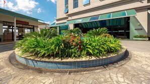 A hotel entrance with a tiled planter, a green awning, and a sign for 'GRÃO ESPREVO'.