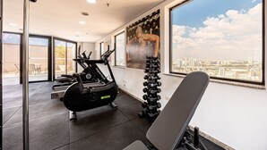 A gym with exercise equipment, large windows, and a city view.