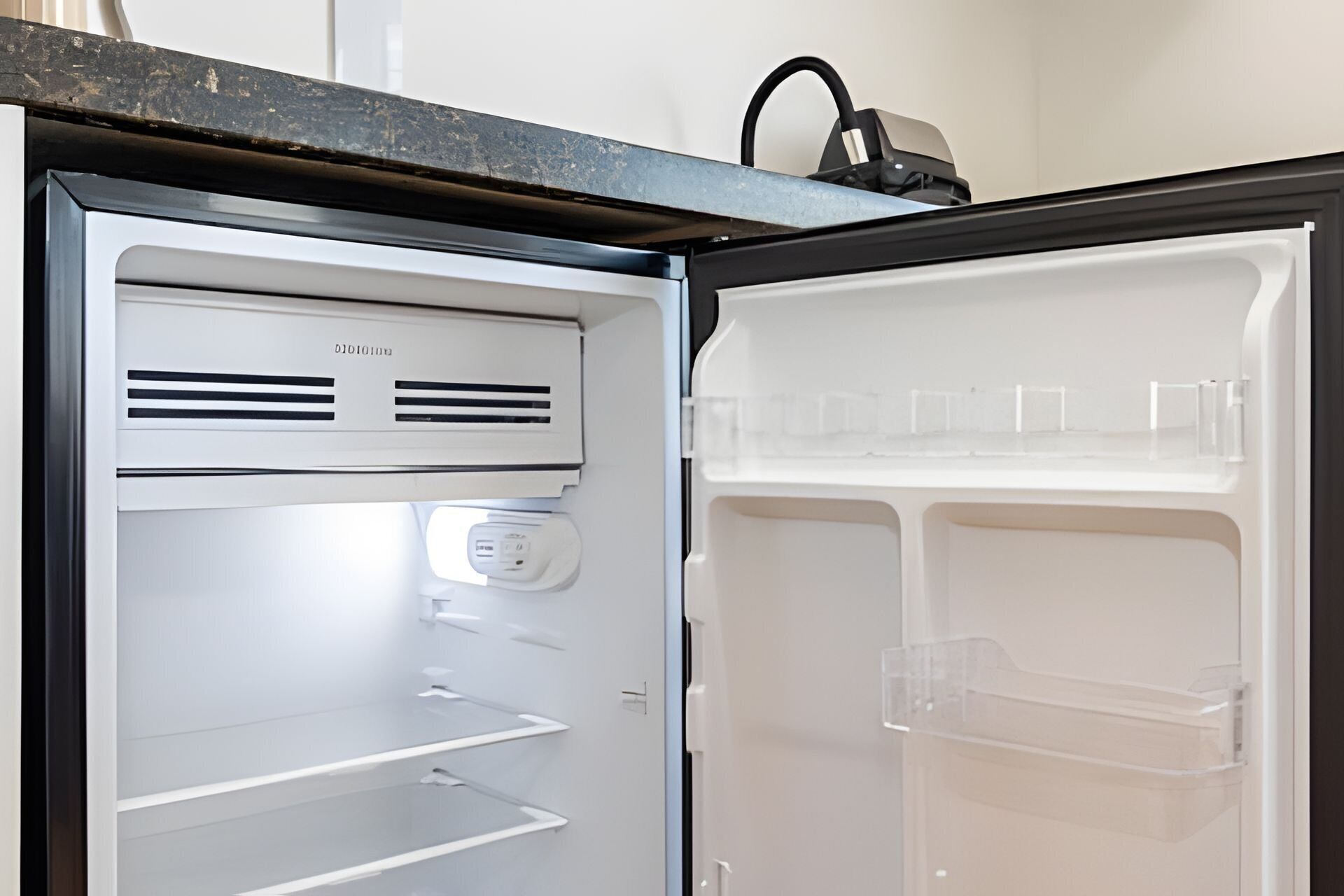 Un refrigerador abierto con un panel de control, un compartimento congelador y una repisa.