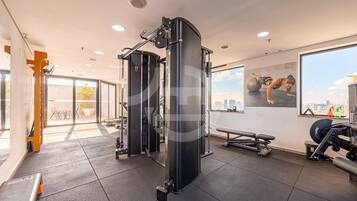 A gym with exercise equipment, a large window, and a view of the city.