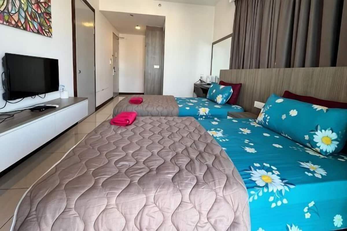 A hotel room with two beds, a TV, a desk, and a bathroom.