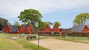 Une rangée de charmantes maisons aux toits rouges, avec un filet de volley-ball en premier plan.