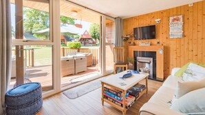 Un salon chaleureux avec une cheminée, un téléviseur et une vue sur la terrasse extérieure.