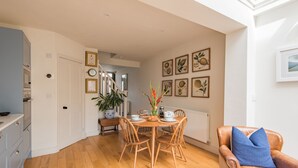 A dining area with a wooden table and chairs, a bench, and a potted plant. - Wisteria Cottage, Deal (Deal)