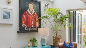 A room with a teal cabinet, a brown leather chair, a blue pillow, a large potted plant, and a framed picture of a historical figure. - Wisteria Cottage, Deal (Deal)