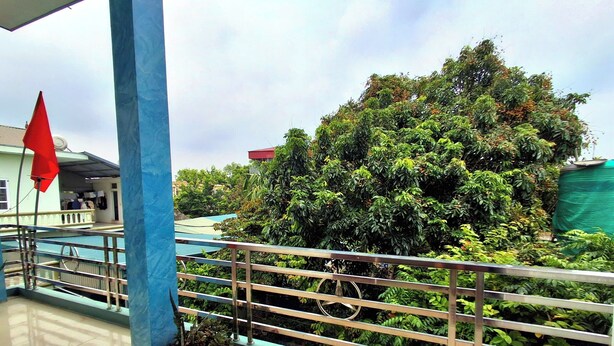A balcony with a metal railing, a potted plant, and a red flag. - Immersive Homestay NinhBinh  (Dai Hoang)