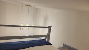Un dormitorio con una cama, cabecera de madera y una lámpara colgante.