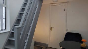 A staircase leading to a landing, a white door, and a small table with a chair.