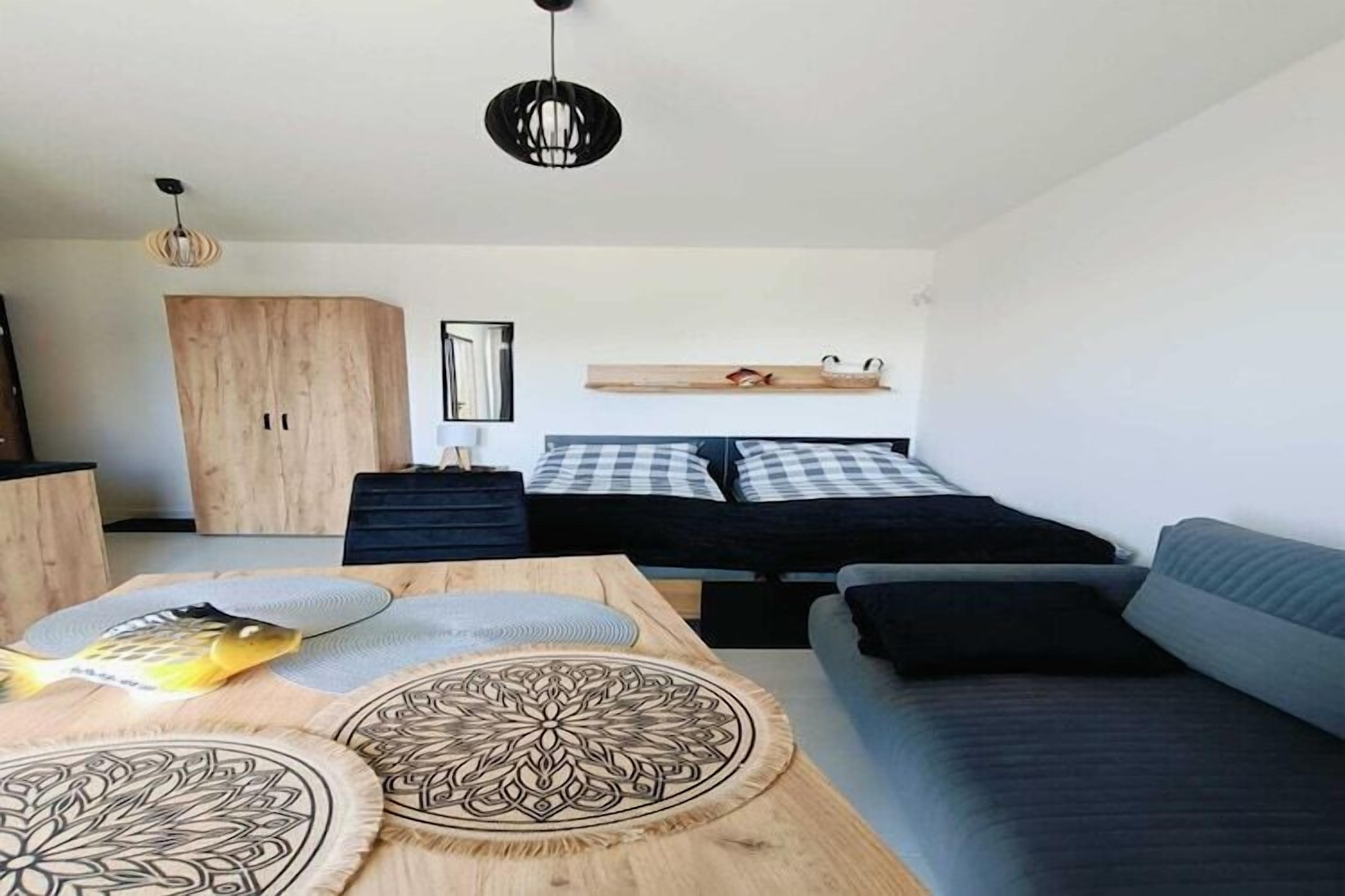A modern room with a bed, a sofa, a wooden table with decorative items, and a wardrobe.