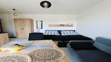 A modern room with a bed, a sofa, a wooden table with decorative items, and a wardrobe.