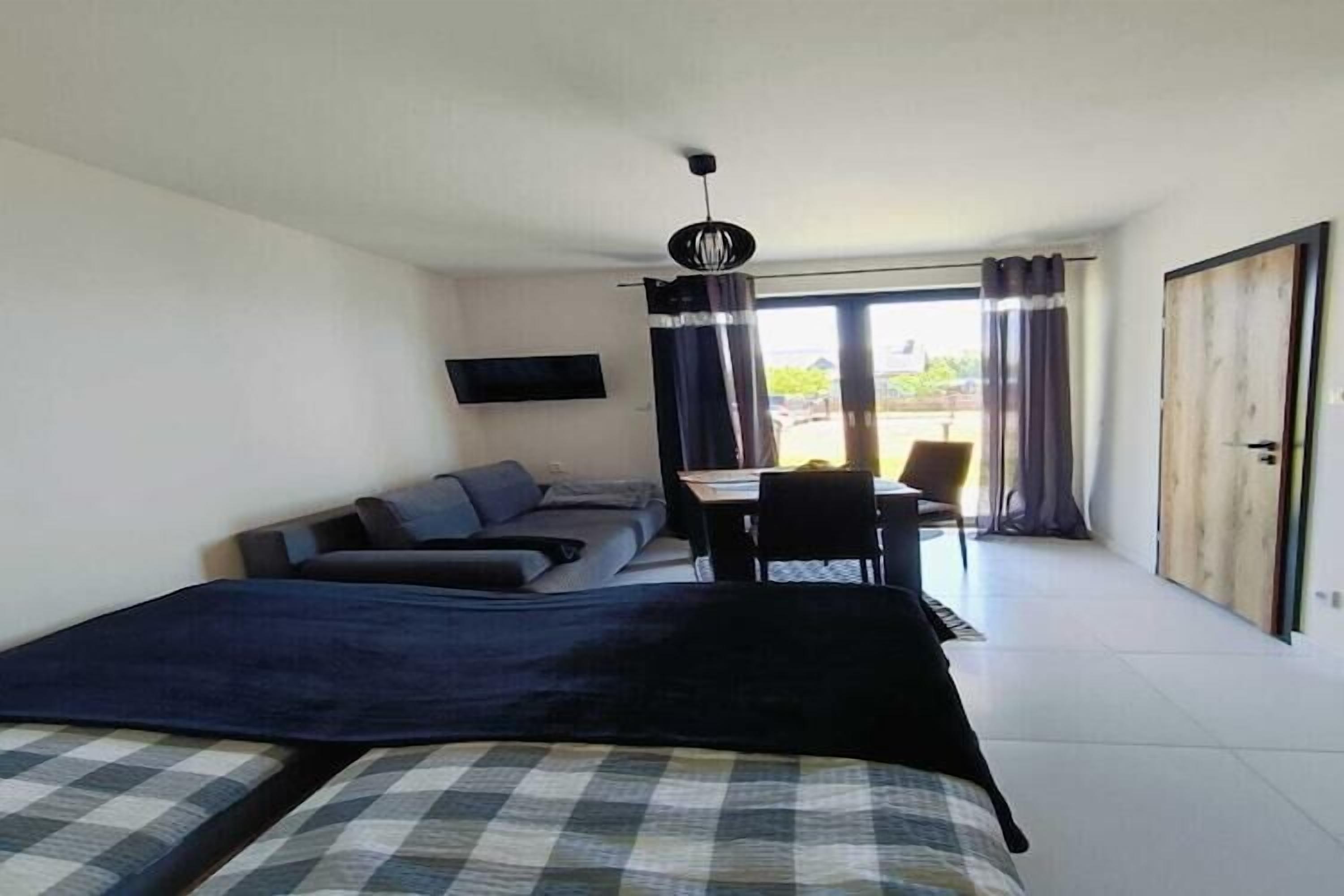 A modern bedroom with a bed, a sofa, a desk, and a TV.