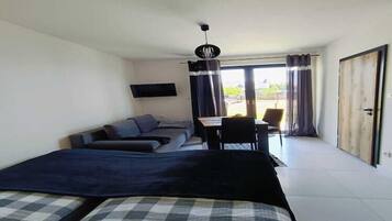 A modern bedroom with a bed, a sofa, a desk, and a TV.