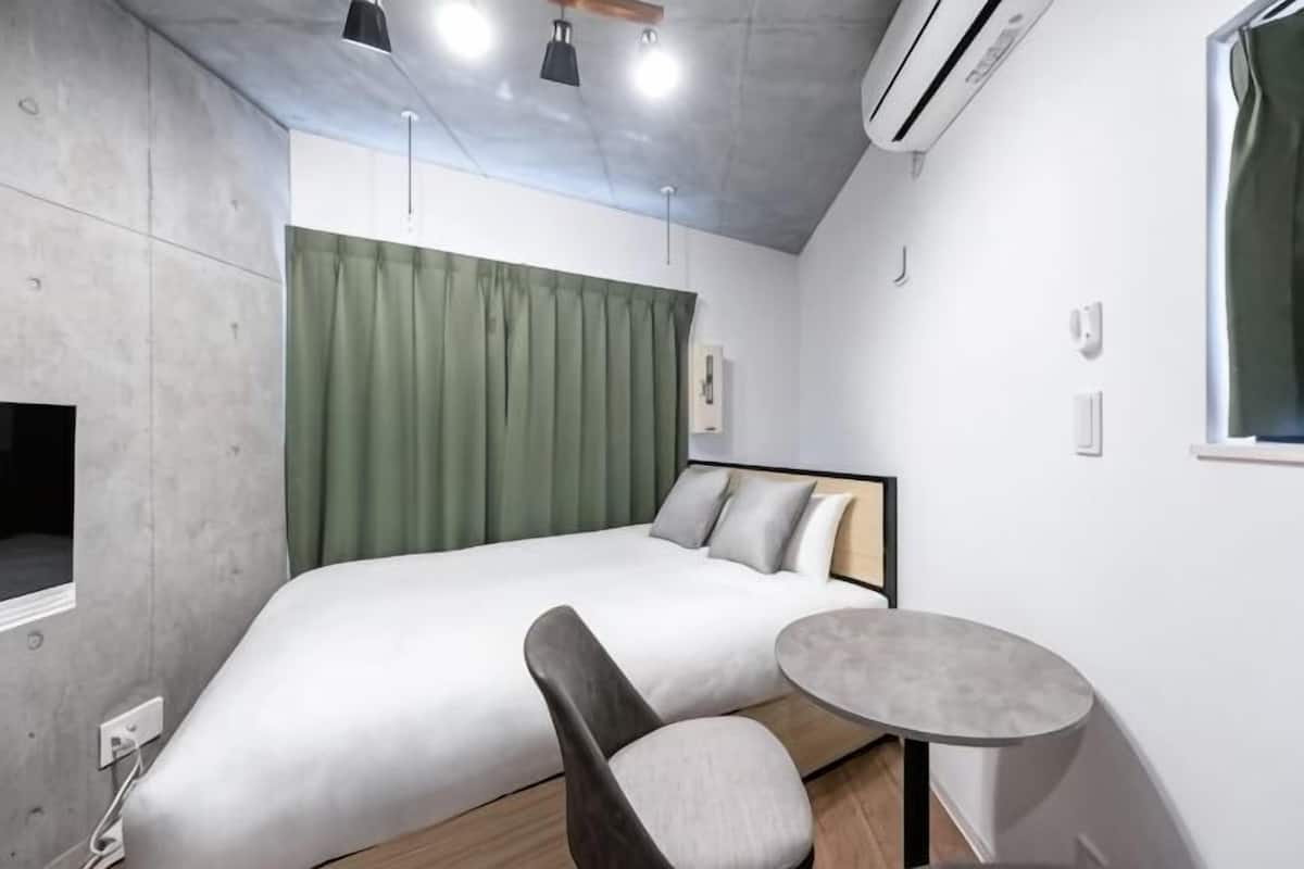 A modern hotel room with a bed, a round table, and a TV.