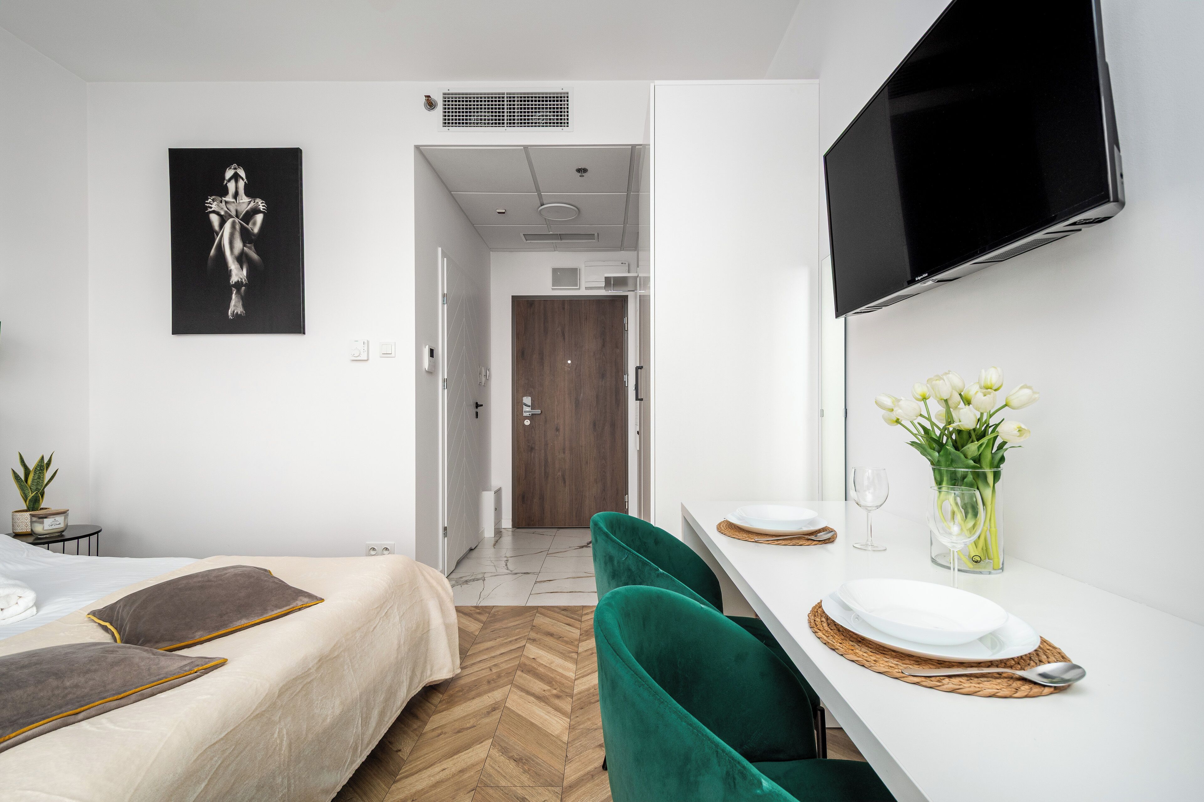 Een moderne hotelkamer met een bed, bureau, flatscreen televisie en een schilderij aan de muur.