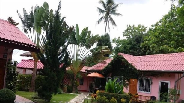 A pink building with a red roof, surrounded by lush greenery and a stone pathway. - Khuang Na Farmview (Mae Chaem)