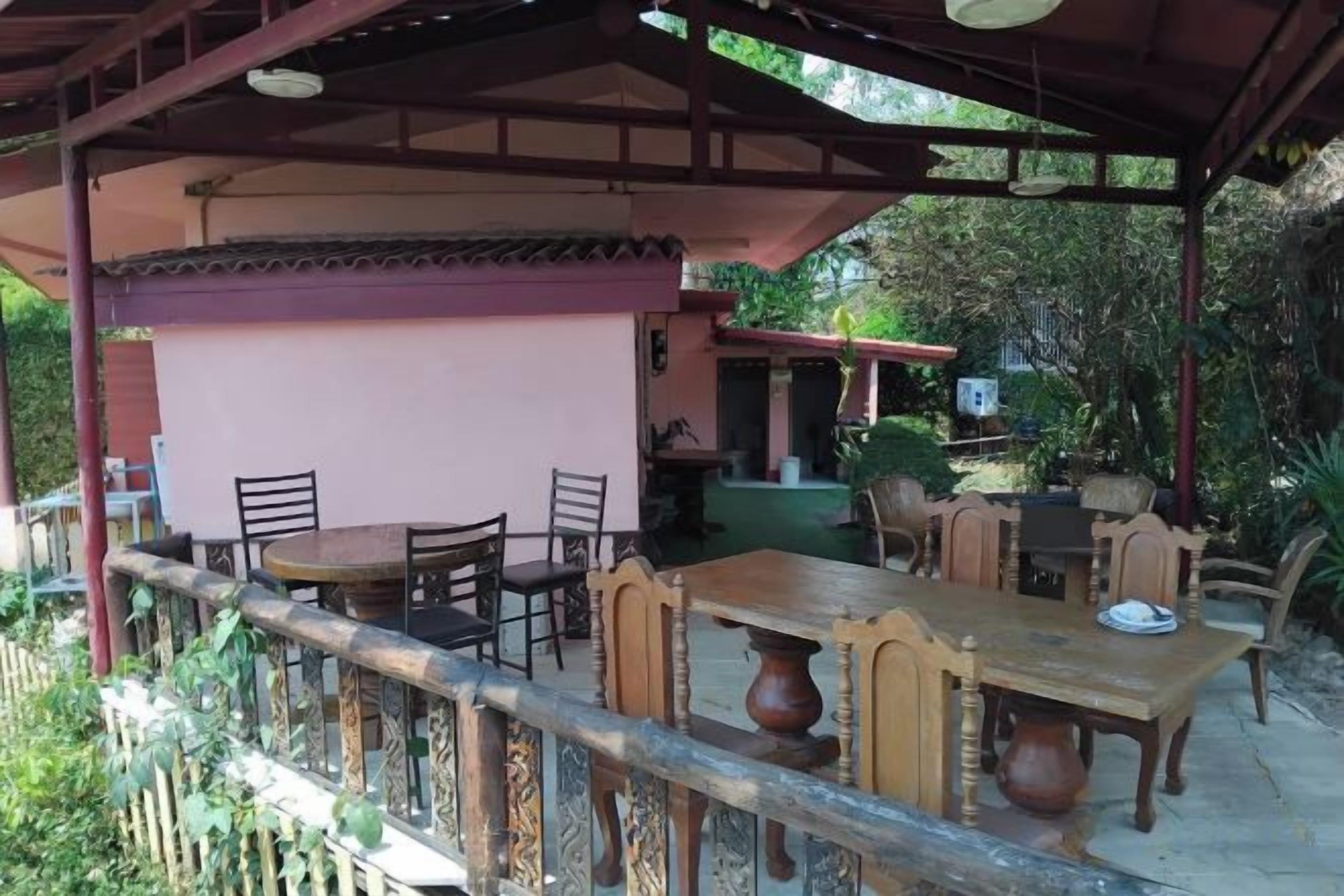 An outdoor patio with a table and chairs, a covered seating area, and a view of the surrounding greenery.