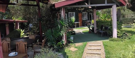 A covered outdoor seating area with a stone pathway leading to a door.