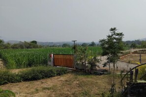 A rural landscape with a field, a wooden gate, and a small structure. - Khuang Na Farmview (Mae Chaem)