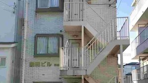 Un edificio residencial de varios pisos con fachada de ladrillo, balcones y una escalera visible.